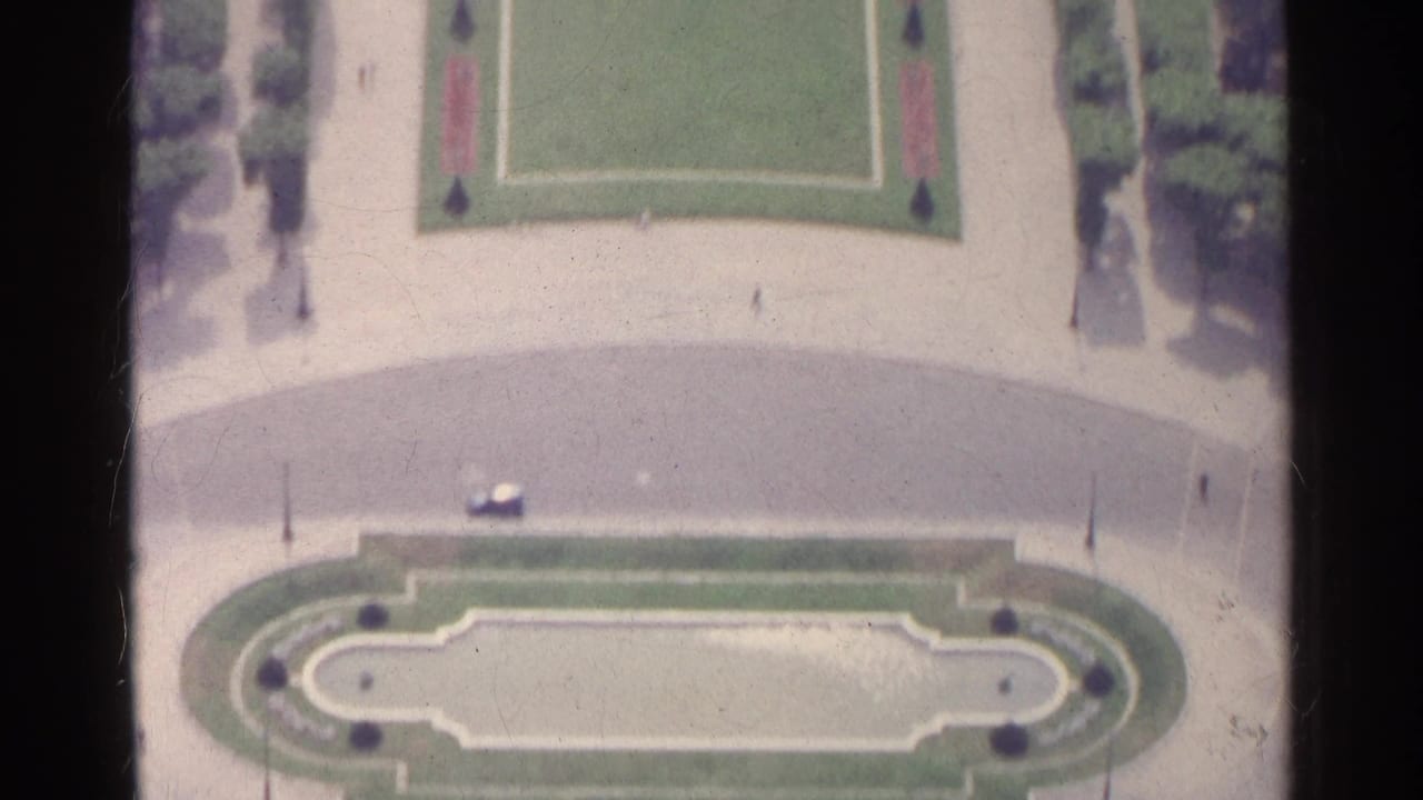 Elevated view of a formal garden with lawns, paths, and an oval planted feature.