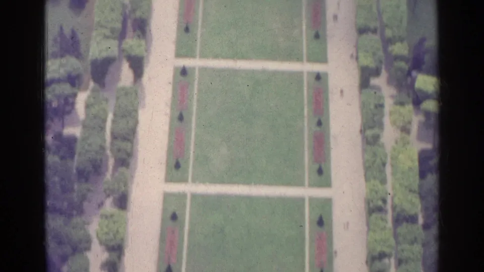 1961 Paris home-movie view looking down on formal lawns, broad walkways, tree borders, and symmetrical ornamental planting beds.