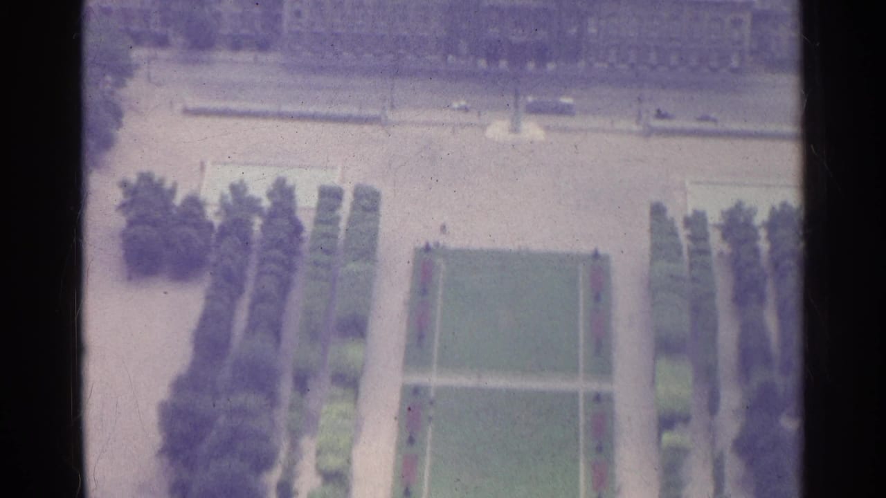 1961 Paris 8mm frame showing an elevated view over formal gardens, a rectangular lawn, trees, and paved approaches.
