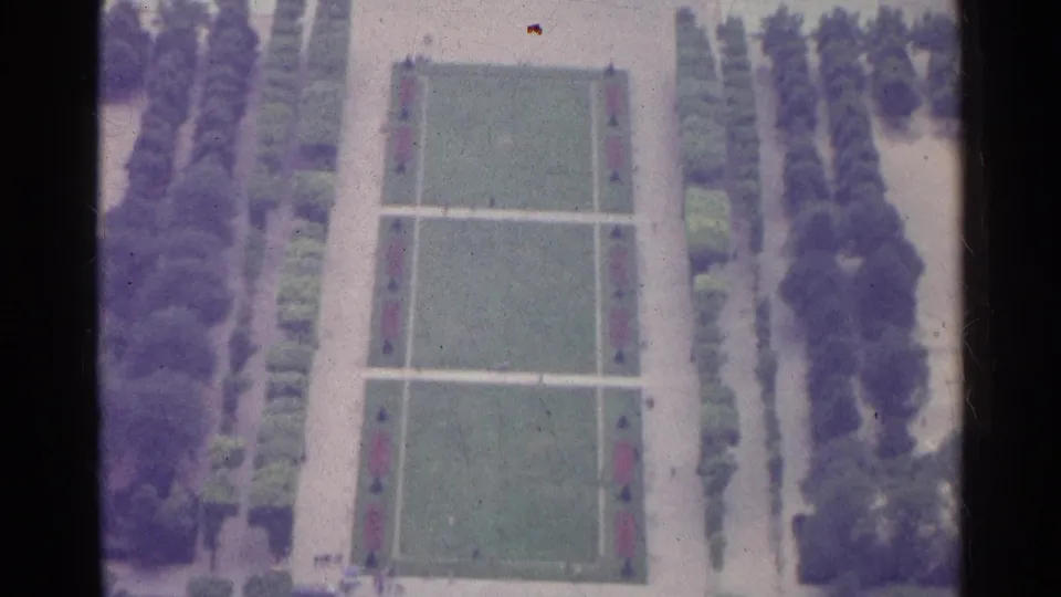 1961 Paris 8mm frame with a clearer elevated view of symmetrical garden paths, lawns, trees, and paved borders.