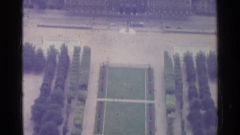 1961 Paris 8mm frame showing a soft, purple-tinted elevated view of formal lawns, paths, and surrounding trees.