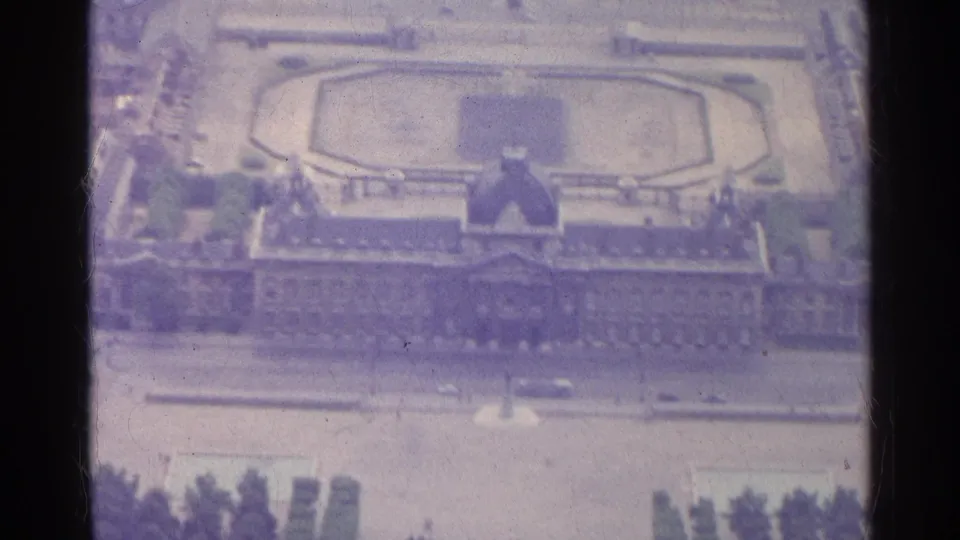 1961 8mm aerial view over Paris showing a formal octagonal garden, palace-like building, streets, and surrounding city blocks.