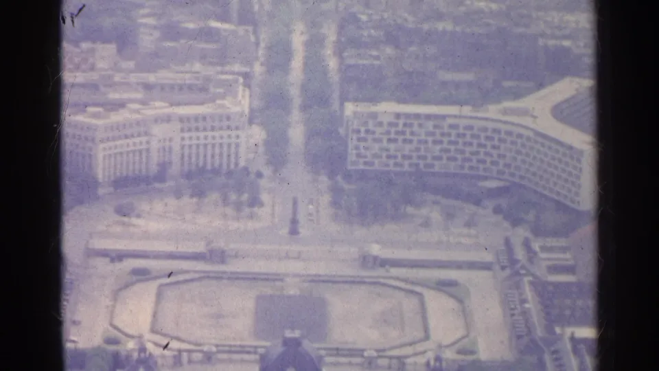 1961 8mm aerial view over Paris, with pale monumental buildings, a wide boulevard, and an octagonal plaza below.