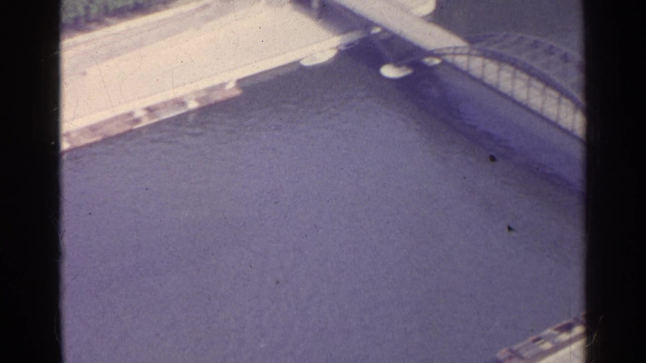 Aerial view of a river edge and bridge structure with dark film borders.