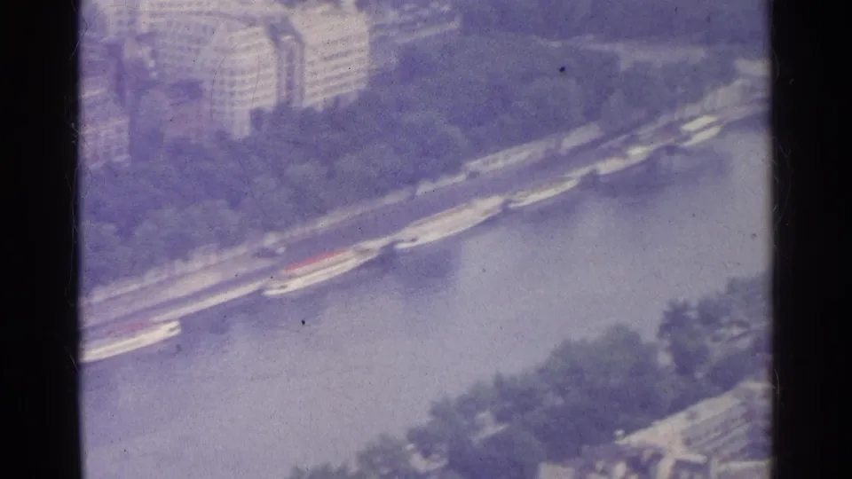 1961 Paris aerial 8mm frame showing the Seine, embankments, bridges, riverboats, and nearby urban buildings.