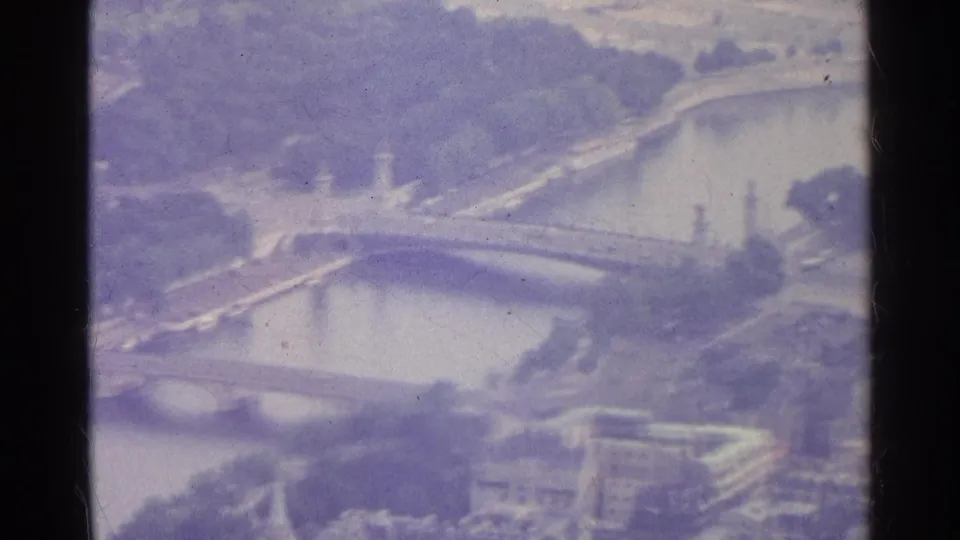 1961 Paris 8mm aerial frame showing a bridge crossing the Seine, nearby parkland, boats, roads, and riverside architecture.
