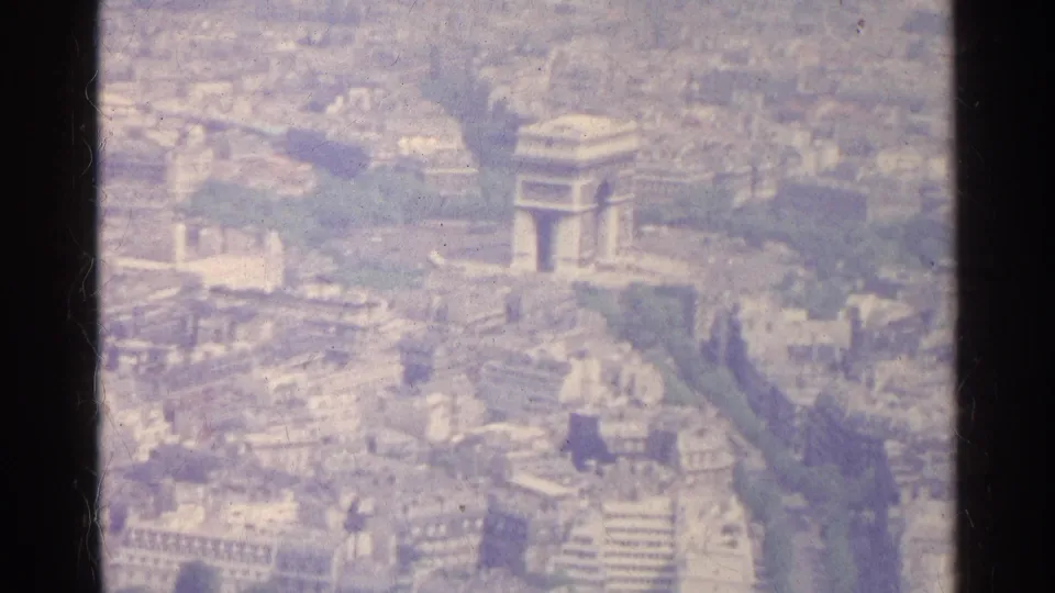 1961 Paris aerial frame showing the Arc de Triomphe surrounded by dense city blocks and broad radiating avenues.