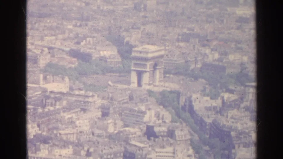 1961 Paris aerial 8mm frame showing the Arc de Triomphe area surrounded by dense city blocks and green avenues.