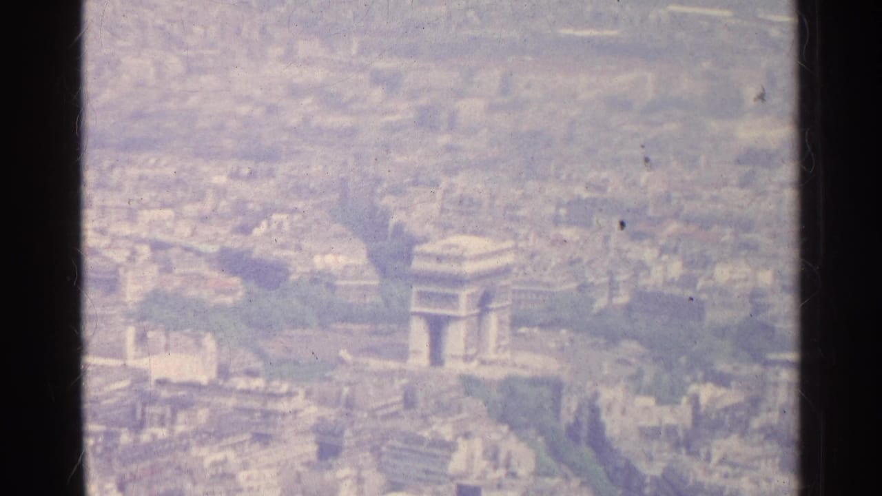 Aerial Paris view with the Arc de Triomphe shifted right of center and city blocks beyond.