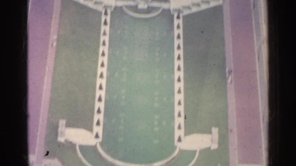Close aerial 8mm frame of a green marked ground area in Paris, bordered by reddish paved surfaces and pale geometric features.