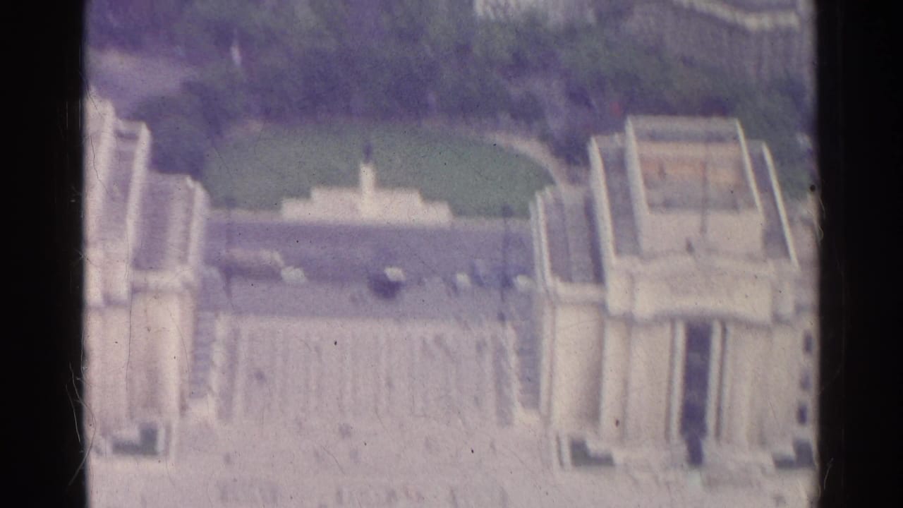 1961 Paris 8mm frame showing a high view over a formal lawn, terraces, stairways, and pale monumental buildings.