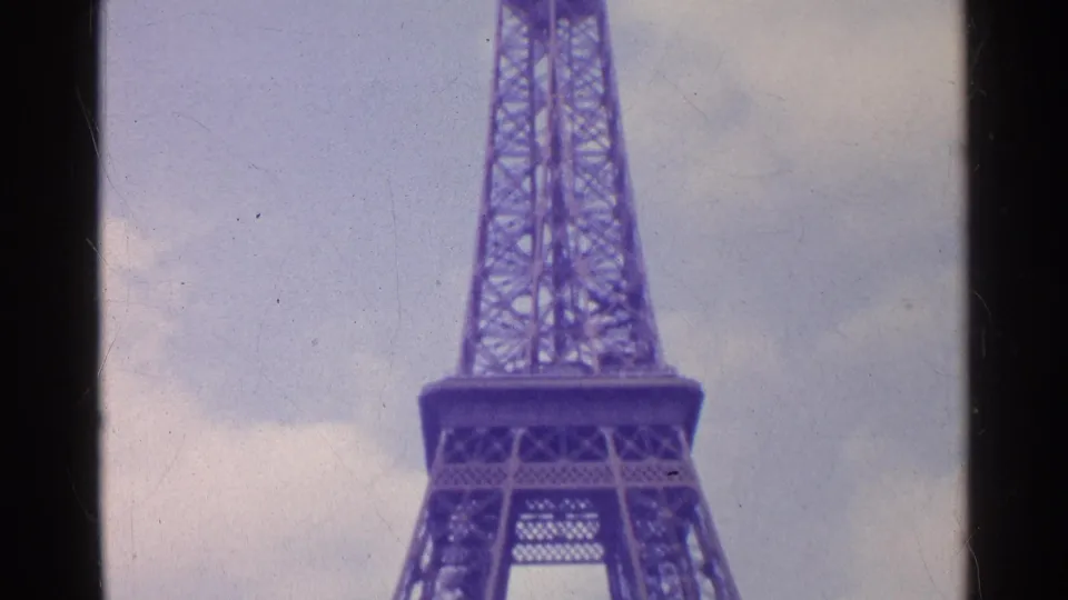 Low-angle 1961 8mm view of the Eiffel Tower with the lower deck and tall lattice form visible.
