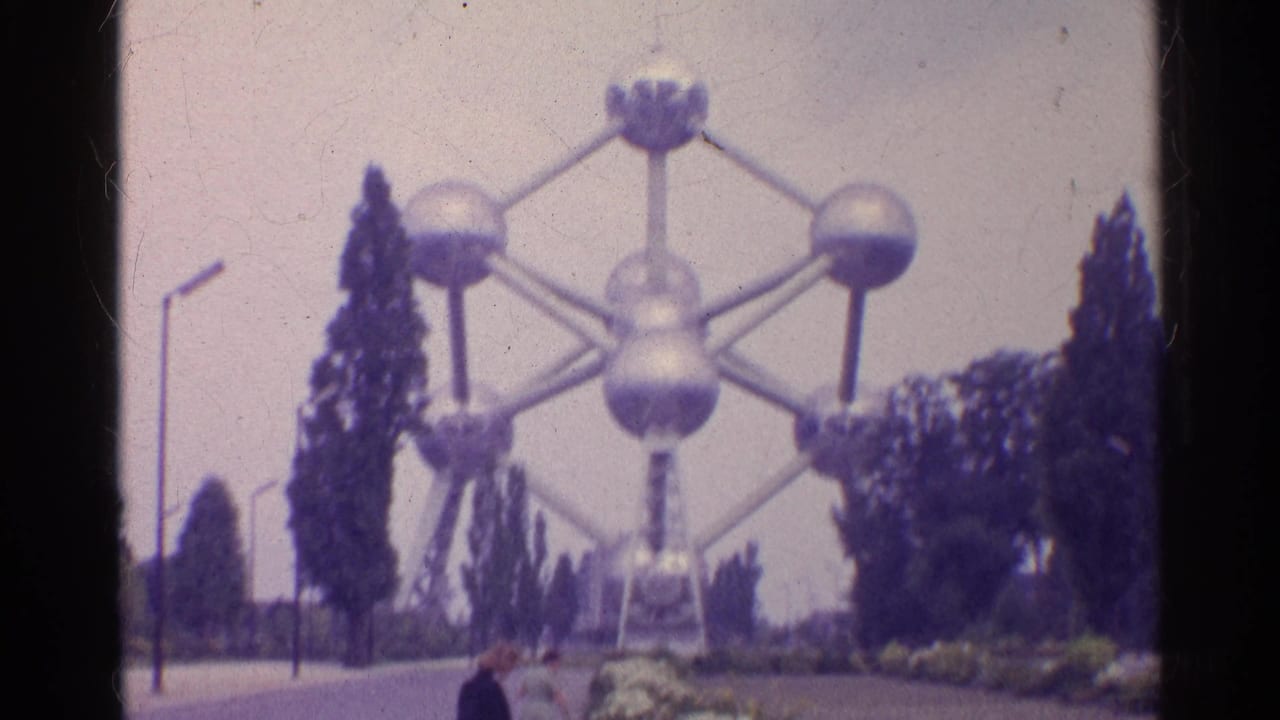 The landmark fills the frame from a visitor path, with tall trees and landscaping around the base in faded 8mm color.