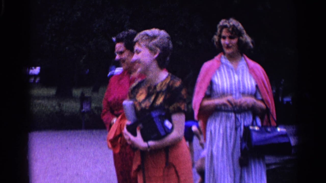 Three adult women in 1960s-style clothing stand together in a Swiss park, laughing and carrying handbags.