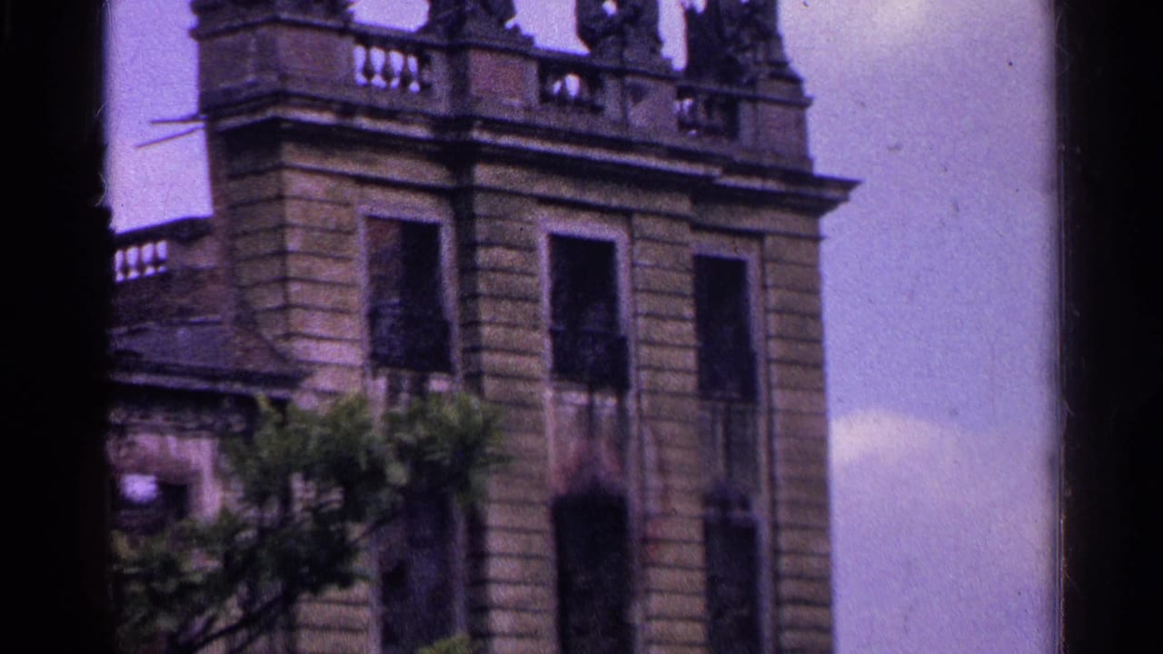 Closer view of the building roofline with carved figures and tall windows.