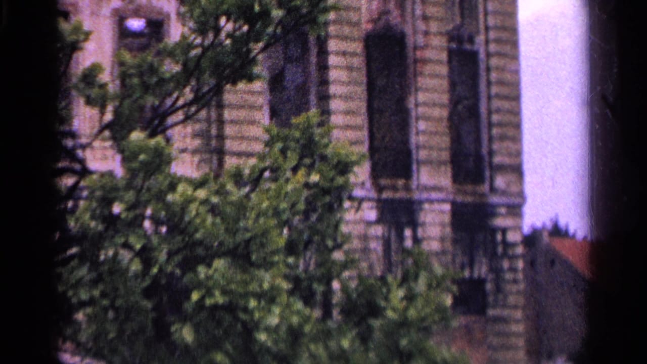 1961 Switzerland 8mm frame showing a weathered ornate building facade partly obscured by trees and film gate shadows.