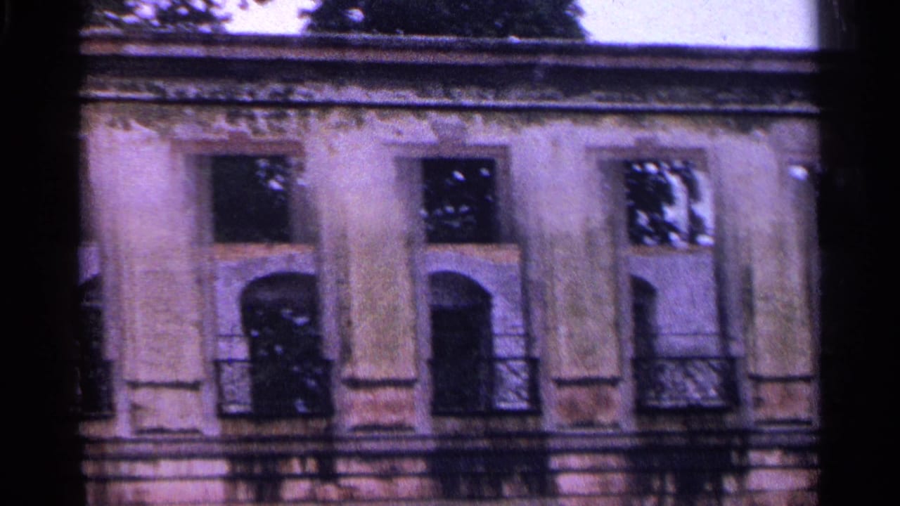 1961 Switzerland 8mm frame showing a weathered ornate facade with arched windows, worn plaster, and tree shadows.