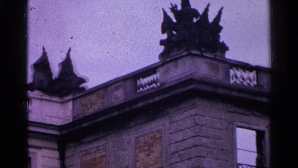 1961 Switzerland 8mm frame of a weathered palace or villa corner with decorative balustrade, roof statues, and open window.