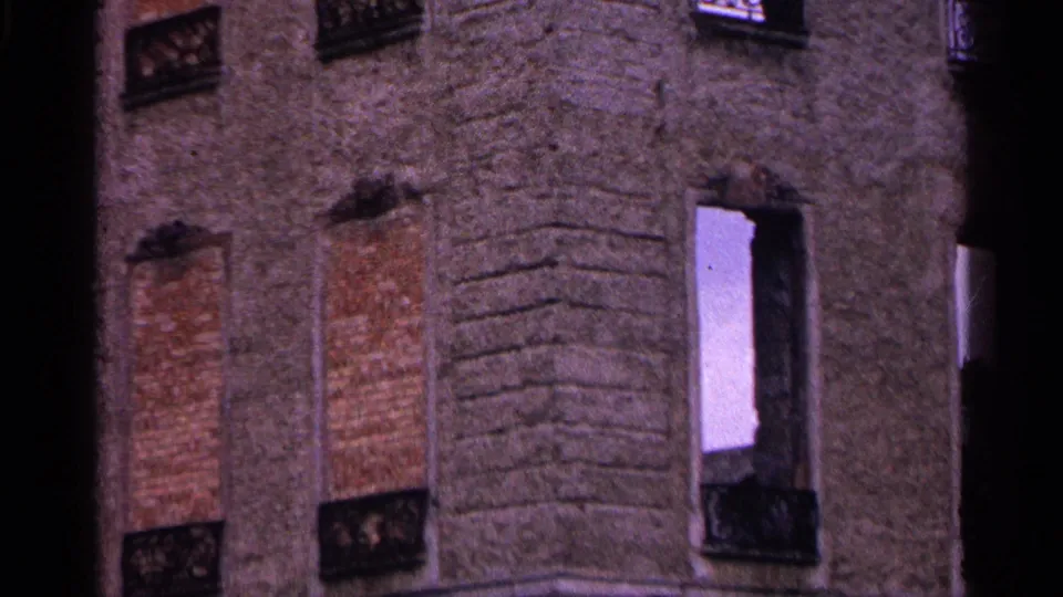 1961 Switzerland 8mm frame showing the lower portion of the weathered facade, with boarded openings, an open white window frame, and ironwork.
