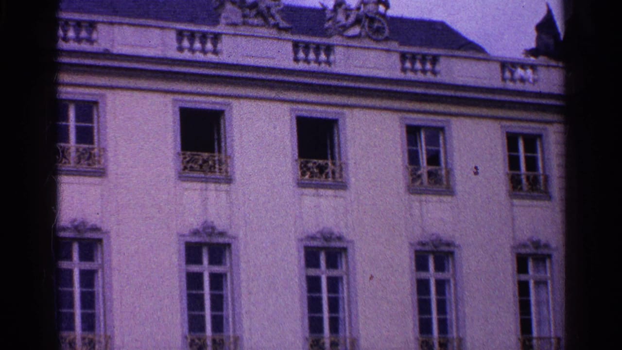 1961 Swiss 8mm frame showing the upper facade of an ornate European building with tall windows and decorative railings.