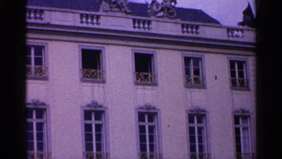 1961 Swiss 8mm frame showing the upper facade of an ornate European building with tall windows and decorative railings.