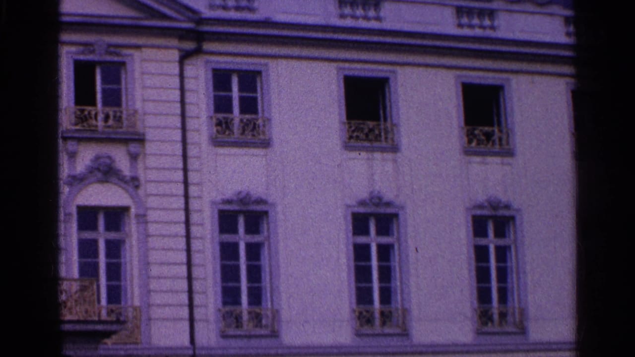 Facade detail with tall windows, small balconies, and a dark vertical frame edge.