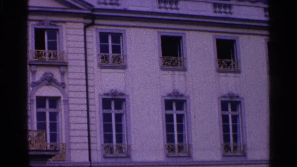 1961 Swiss 8mm view across a formal building facade with paired windows, decorative ironwork, and carved trim.