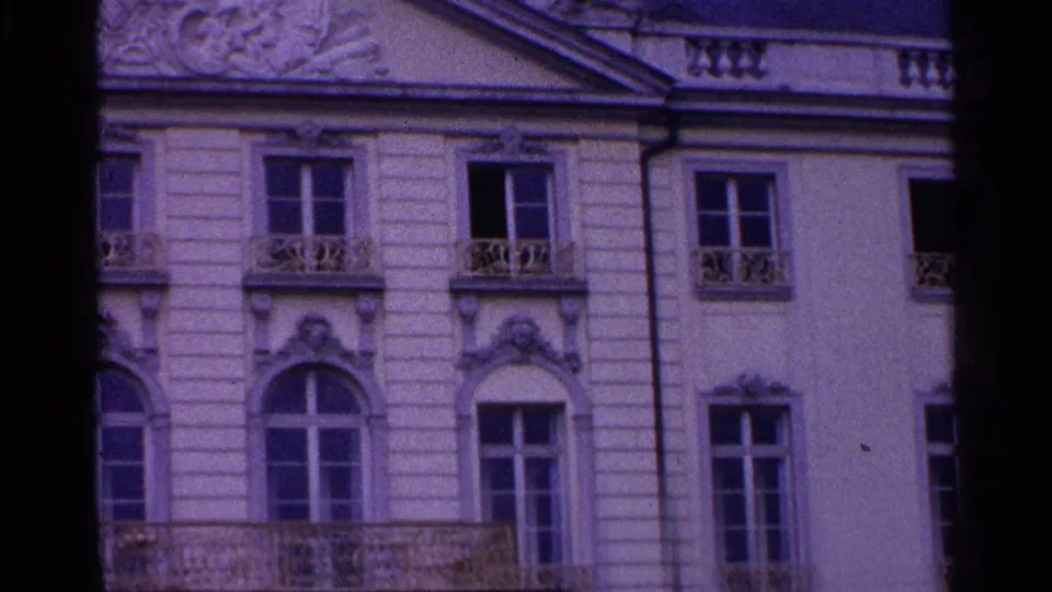1961 Swiss 8mm frame showing lower architectural details, including arched windows, carved trim, and a balcony edge.