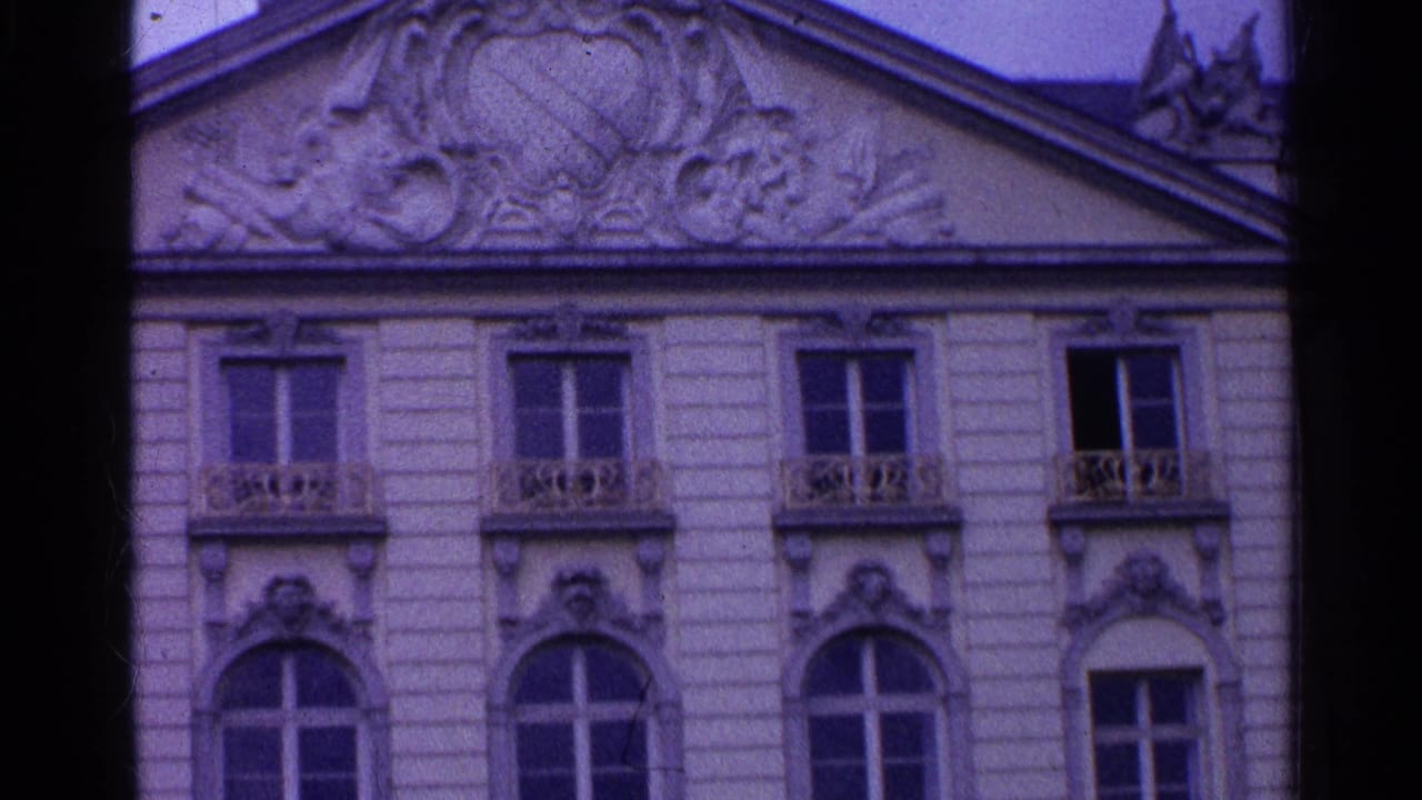 1961 Swiss 8mm frame with sculpted roofline relief, decorative trim, upper windows, and balcony railings.