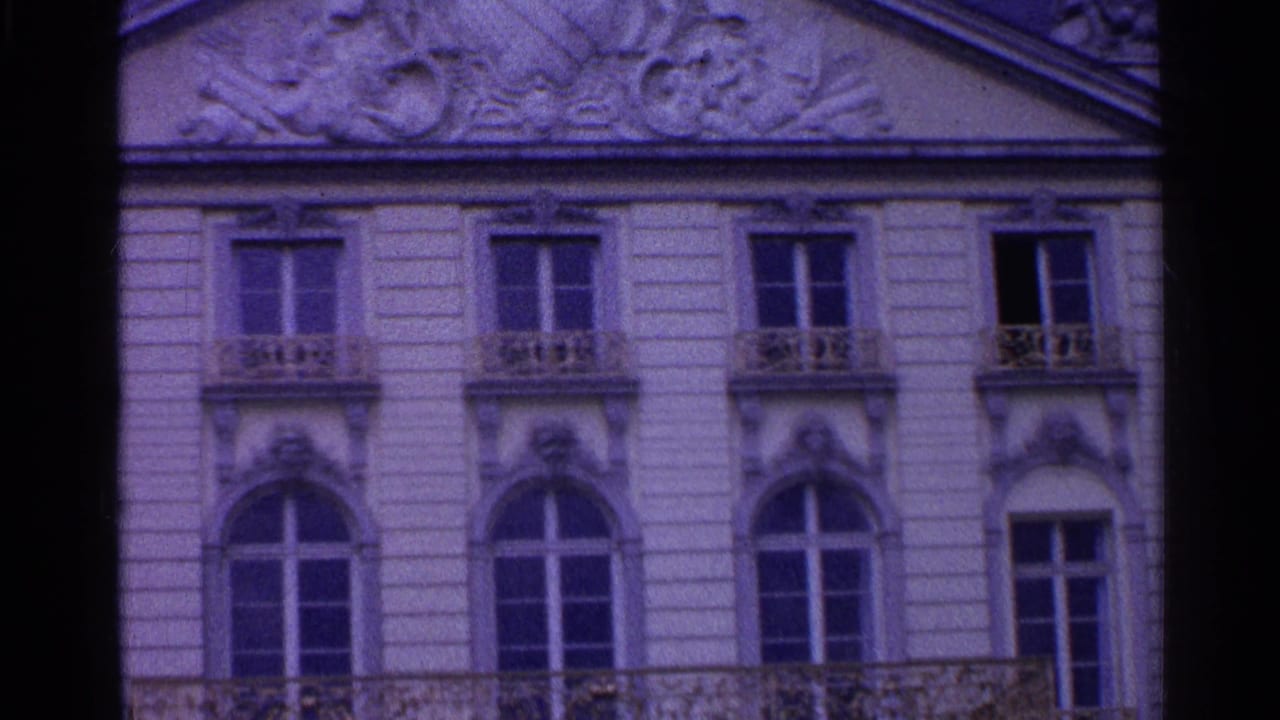 1961 Switzerland home-movie frame showing an ornate European facade with carved trim, arched windows, and decorative balcony railings.