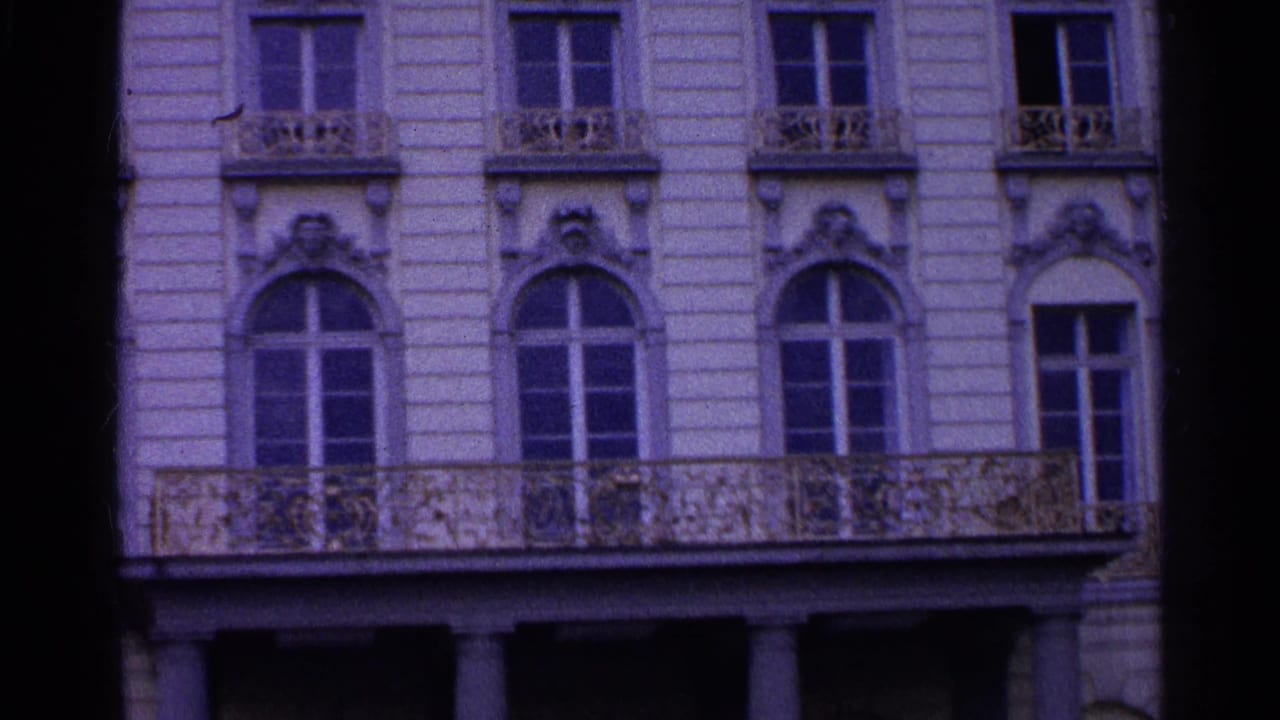 Classical building exterior with balcony, tall windows, and ornamented arches.