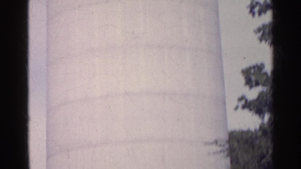 1961 Swiss 8mm frame showing a tall white silo surface against cloudy sky, with film edges and light wear visible.