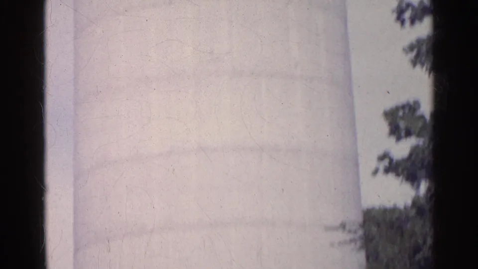 1961 Swiss 8mm frame showing a tall white silo surface against cloudy sky, with film edges and light wear visible.