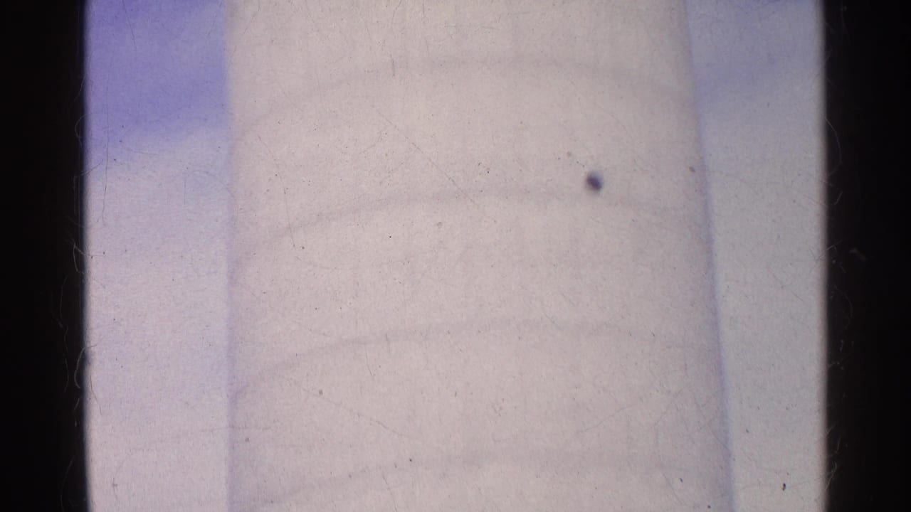1961 Swiss 8mm frame where the white silo fills the view, showing soft focus, pale sky, and visible scan texture.