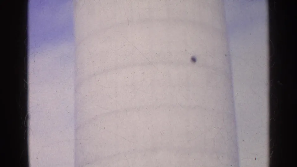 1961 Swiss 8mm frame where the white silo fills the view, showing soft focus, pale sky, and visible scan texture.