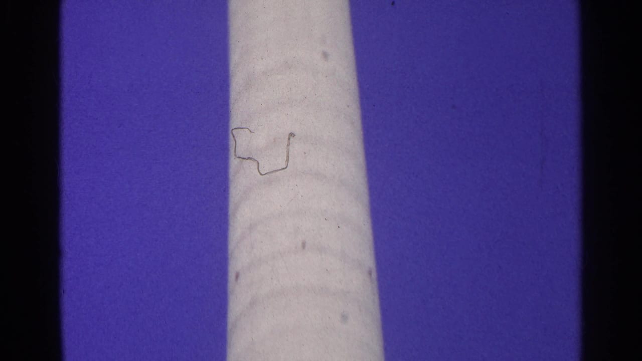 Final 1961 Switzerland frame of a tall pale cylindrical structure against blue sky, showing dust, grain, and slight color shift.
