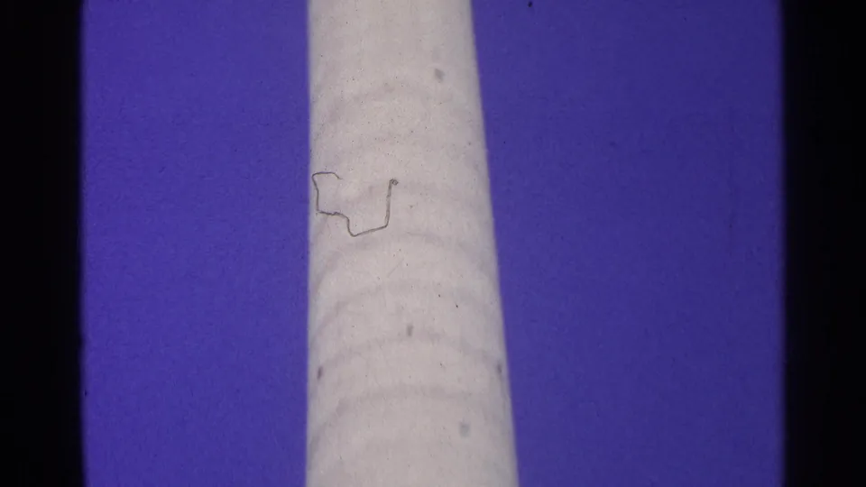 Final 1961 Switzerland frame of a tall pale cylindrical structure against blue sky, showing dust, grain, and slight color shift.