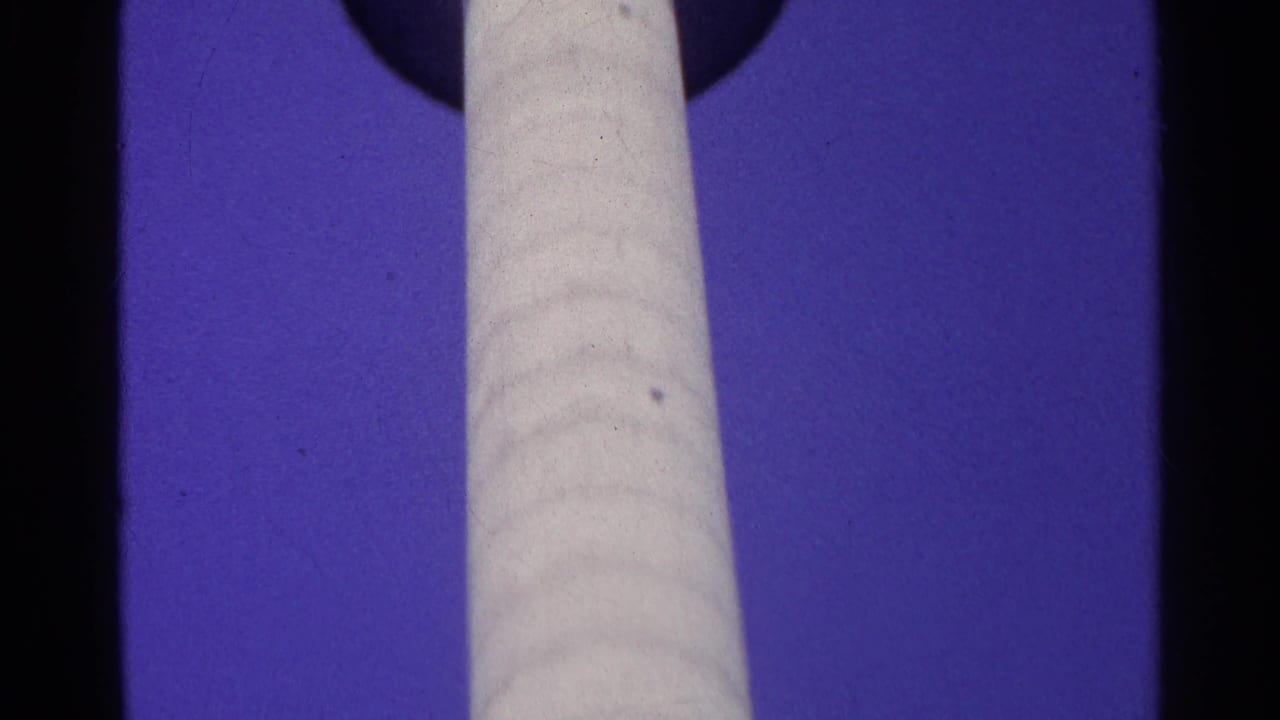 1961 Swiss home-movie frame showing the lower shaft of a tall white TV tower against saturated sky.