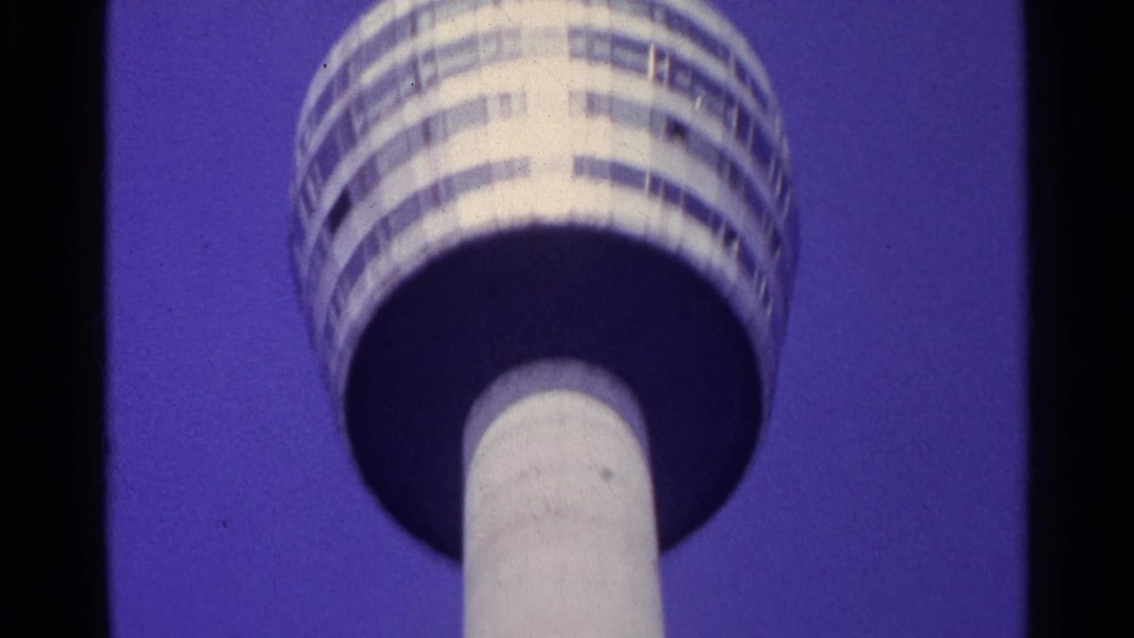 Round observation deck and tower column seen from below against a blue-purple sky.