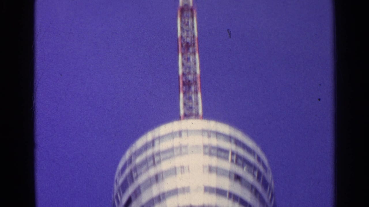1961 Swiss 8mm frame showing the tower's round deck with a tall antenna mast extending upward.