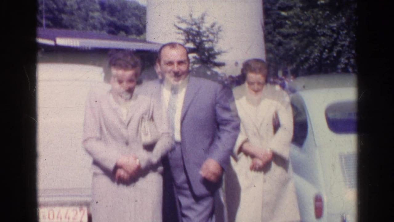 Three adults standing near a pale vintage car in bright daylight.