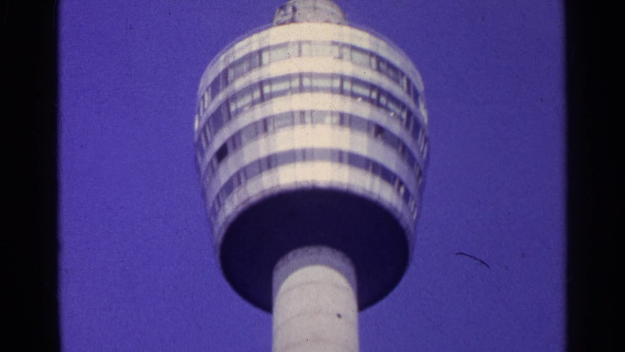 Low-angle view of a tall cylindrical observation tower against a blue sky.