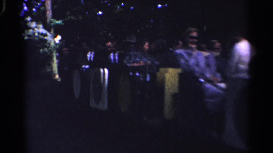 1961 Switzerland 8mm frame showing a small group or line of people at a nighttime outdoor gathering.