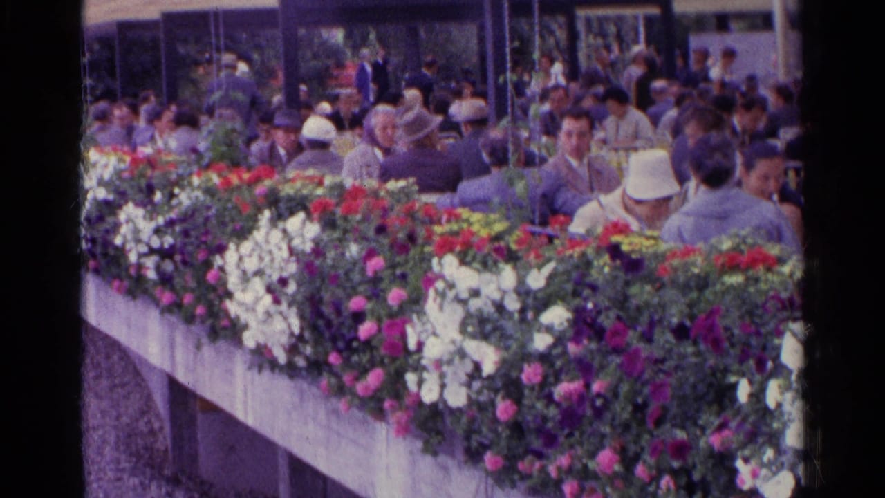 Swiss 1961 home-movie view of a long concrete planter and adults gathered near glass pavilion walls.