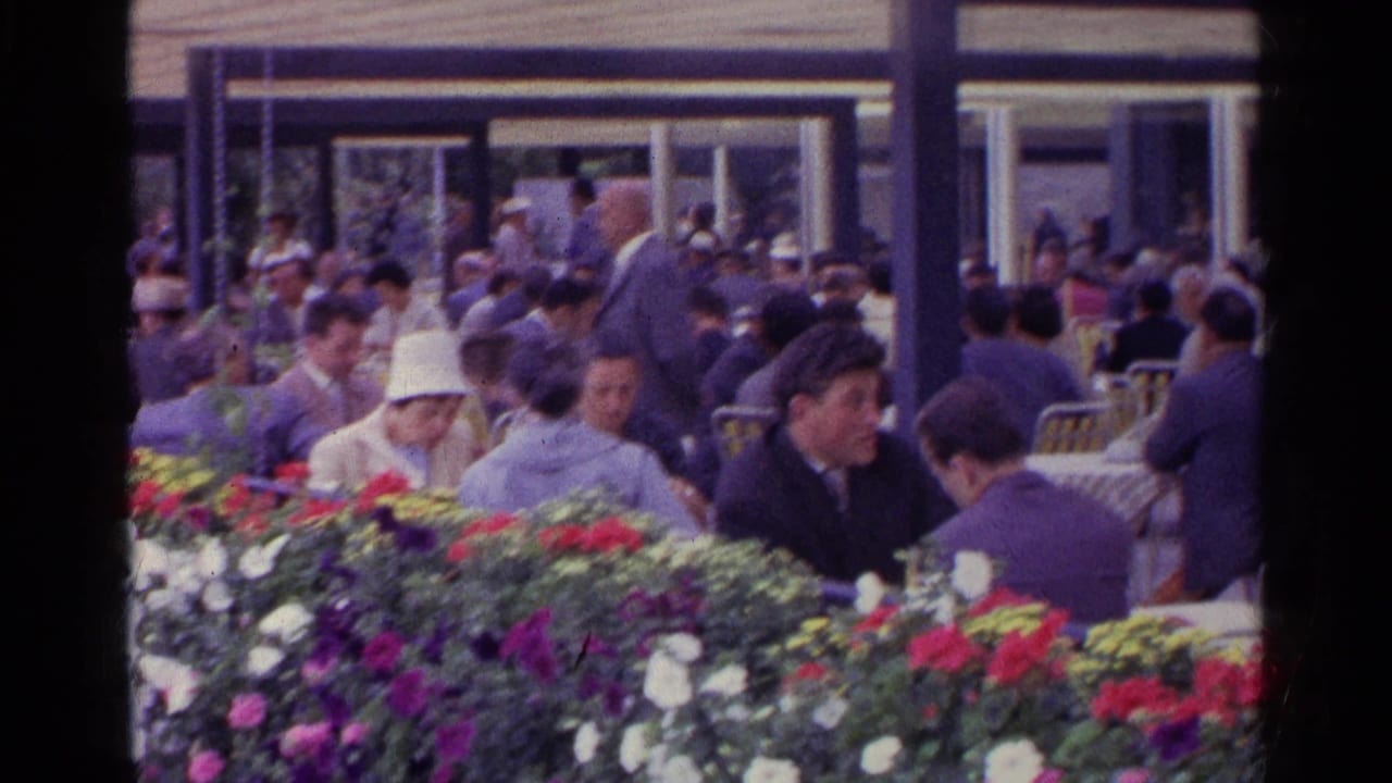 Busy terrace dining area with adults seated near bright flower beds.