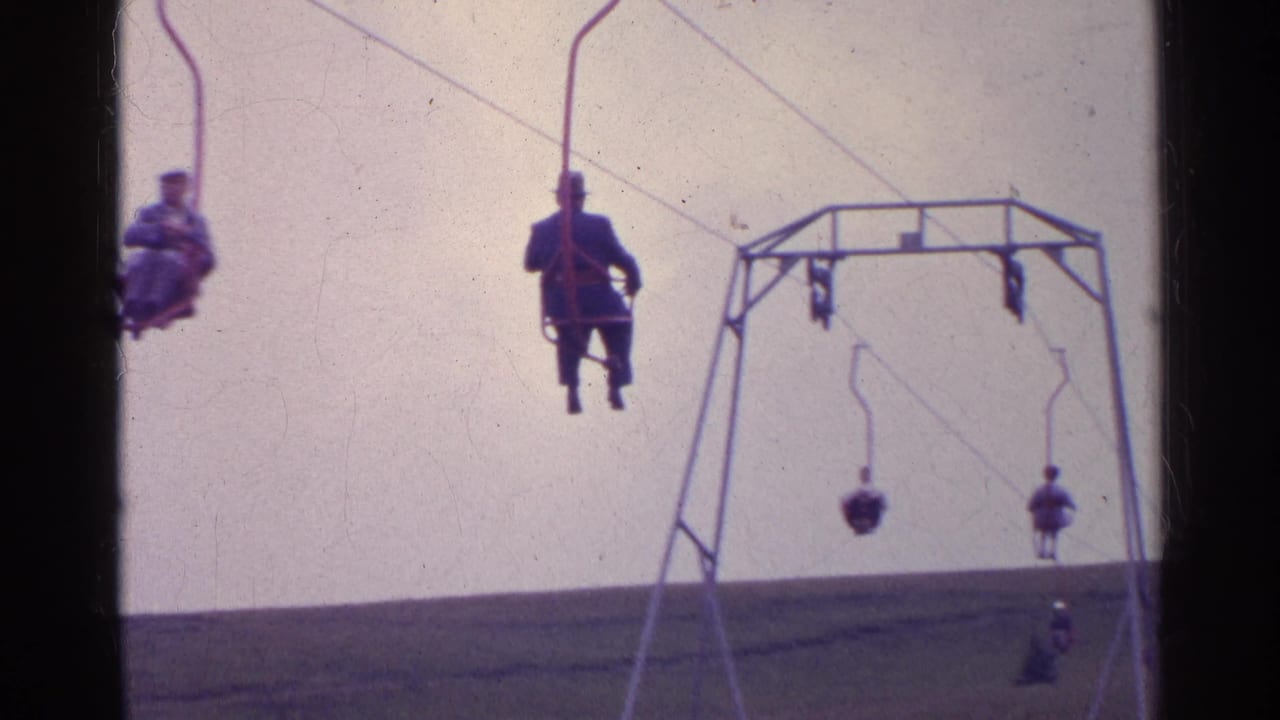 1961 Switzerland home-movie frame showing a foreground ski-lift rider and several distant chairs on an alpine slope.