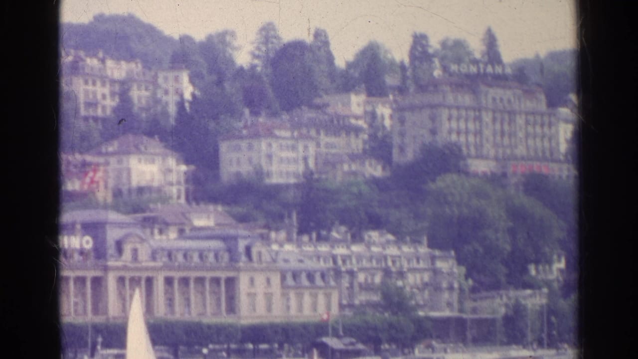 Hillside hotels and casino frontage with lake and a white sail in the foreground.
