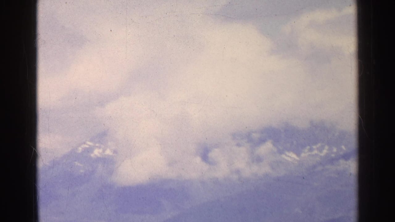 Cloudy sky above distant snow-streaked mountain peaks.