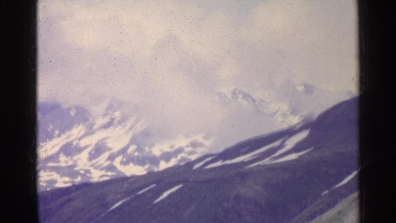 Snow-capped mountains under a pale cloudy sky.