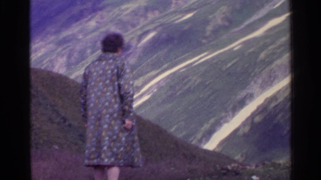 In Switzerland in 1961, a woman in a patterned coat stands with her back to the camera on an alpine slope.